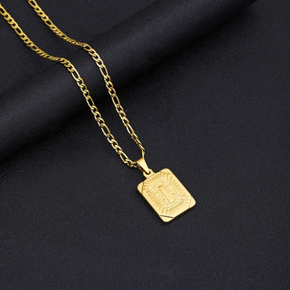 Gold necklace with a square pendant on a black fabric background