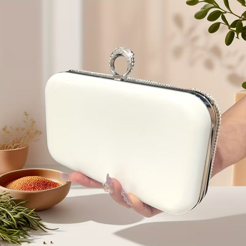 White clutch held by a hand with a blurred background