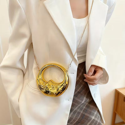 Person carrying a gold bag with a crescent design