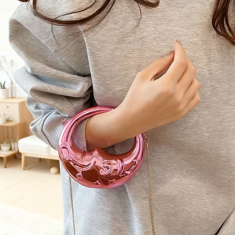Person wearing a pink crescent bag with a chain strap.