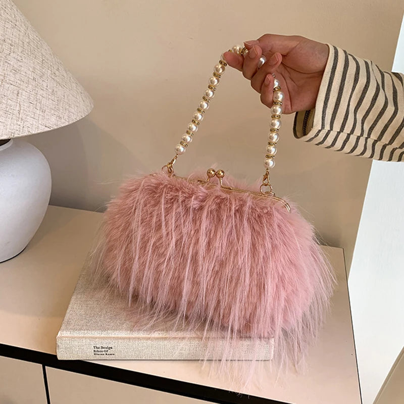 Pink fluffy handbag with pearl handle held by a hand on a light-coloured surface.