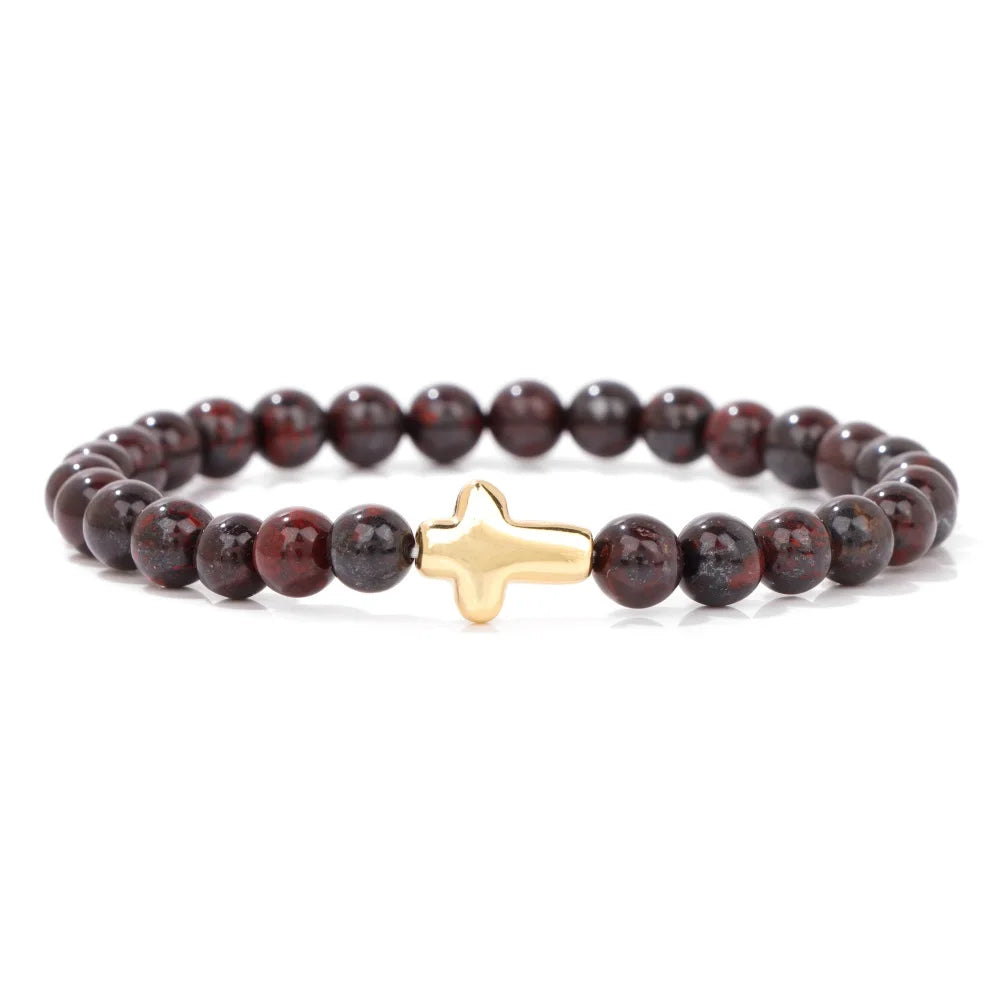 Bracelet with red beads and a gold cross charm on a white background