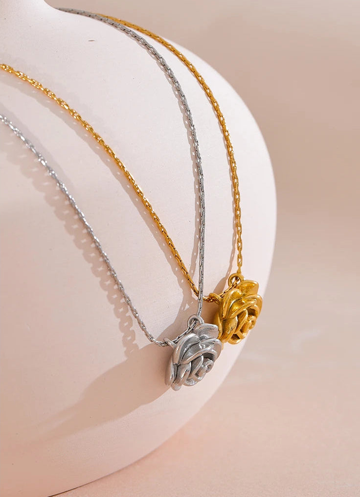 Two necklaces with pendants on a white stand