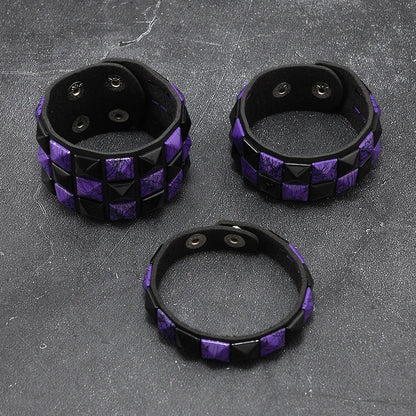 Three black and purple studded bracelets on a textured grey surface