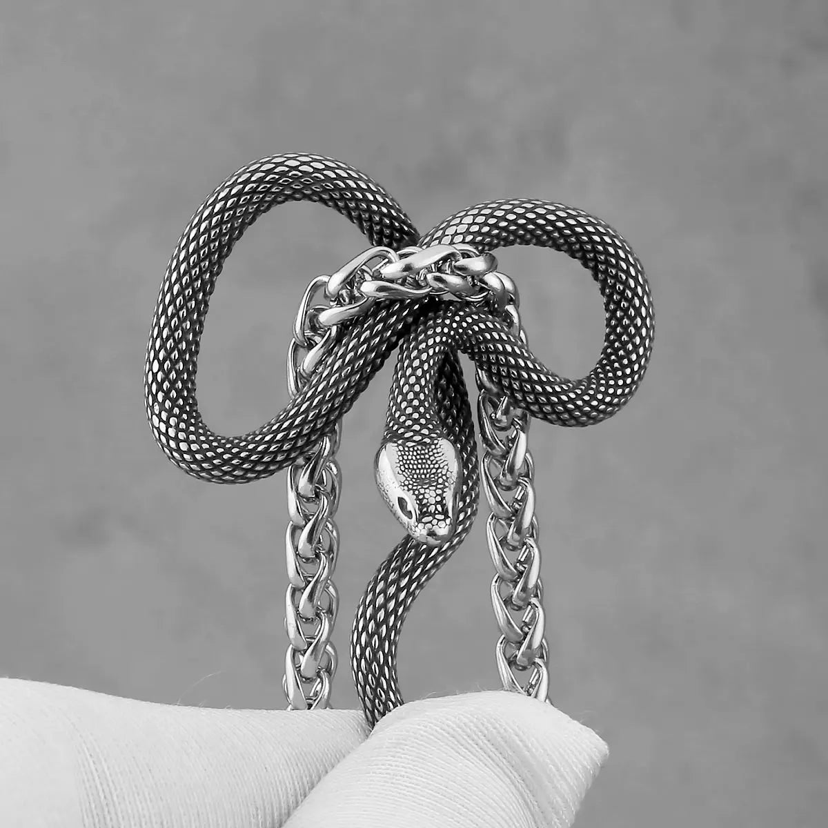 Silver snake-shaped keychain with chain on a grey background