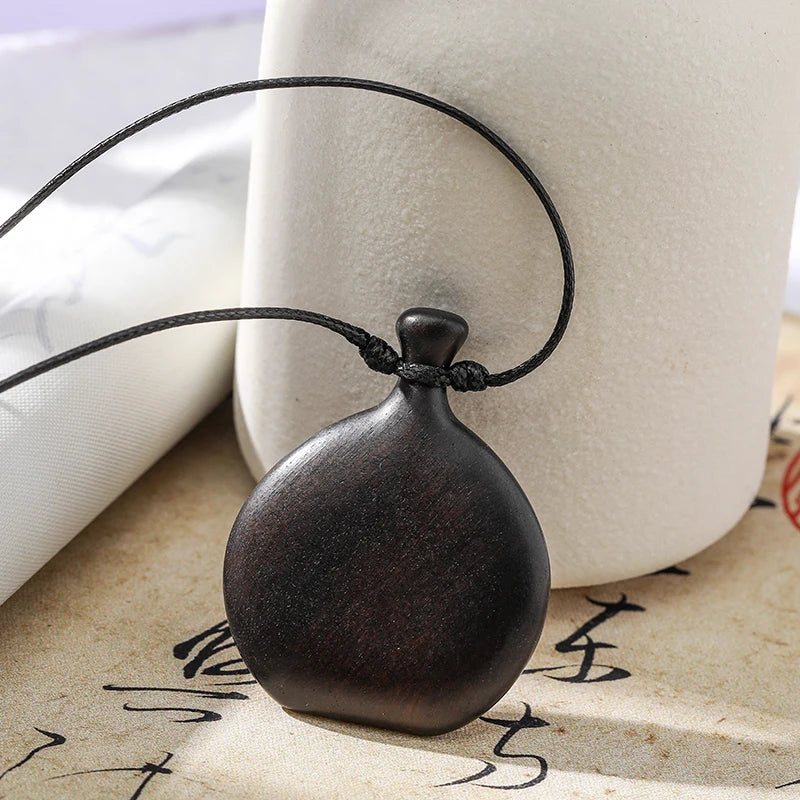 Wooden pendant on a string with a white vase and calligraphy in the background