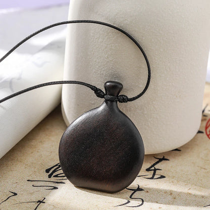 Wooden pendant on a string with a white vase and calligraphy in the background