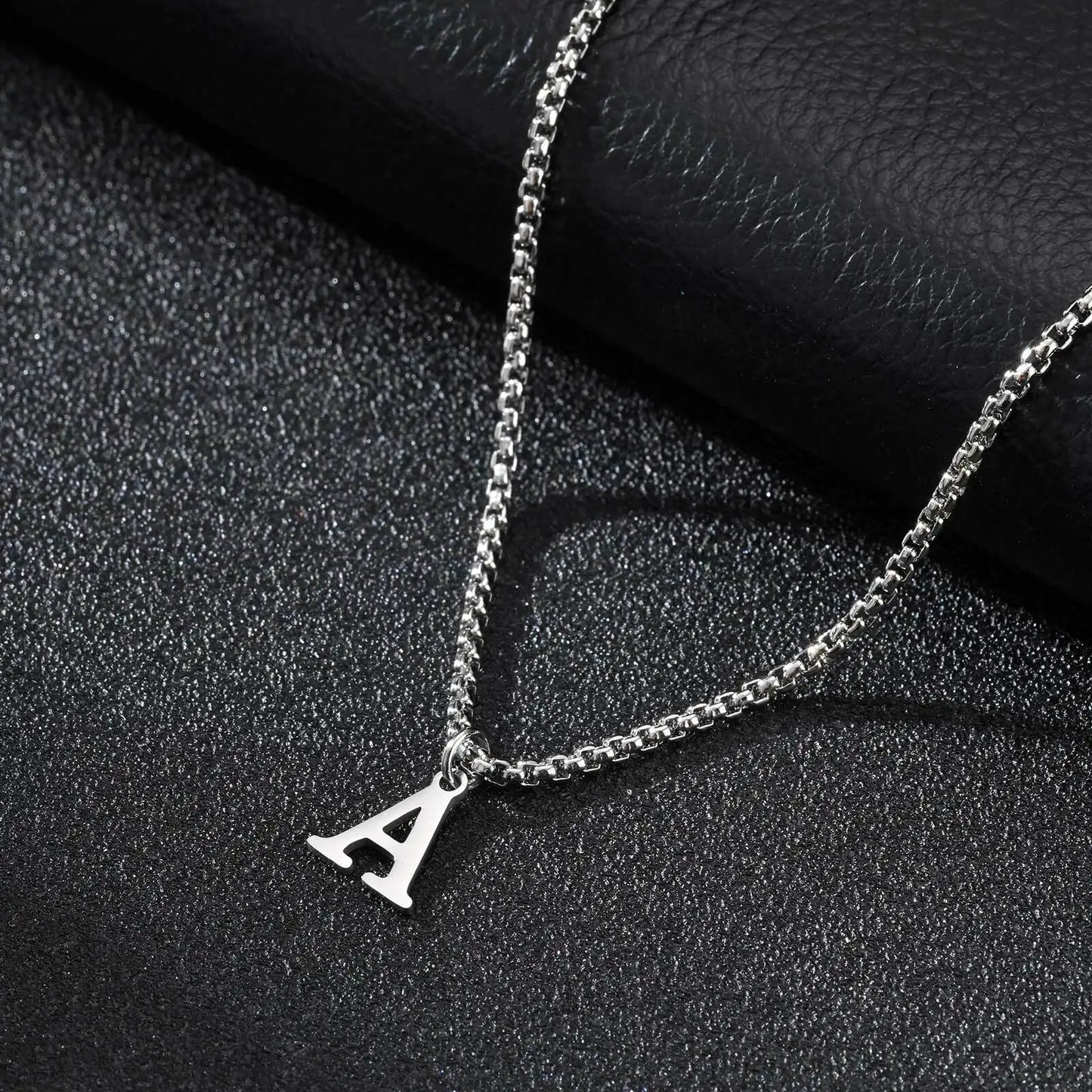 Silver necklace with a 'A' pendant on a dark textured surface