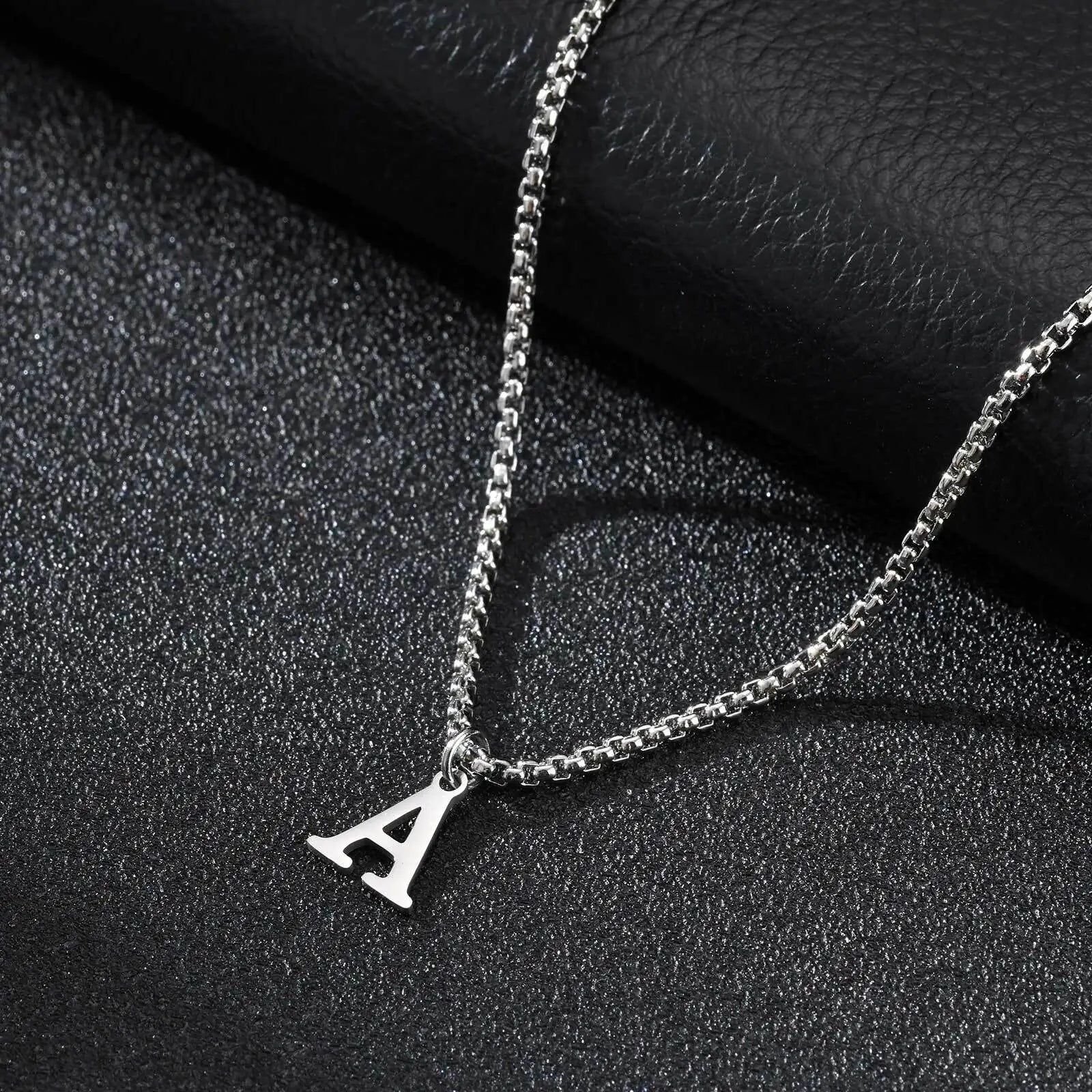 Silver necklace with a 'A' pendant on a dark textured surface