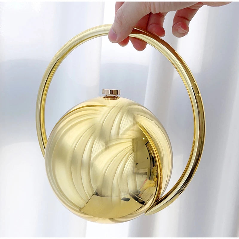 Gold circular handbag held by a hand against a white background