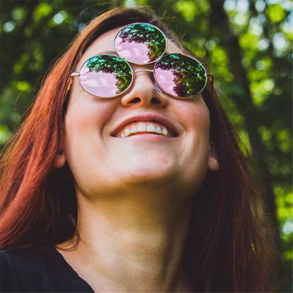 Person wearing reflective sunglasses with a blurred green background