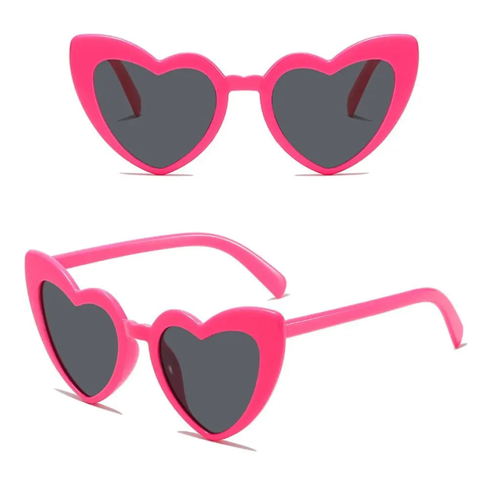 Heart-shaped sunglasses with pink frames and dark lenses on a white background.