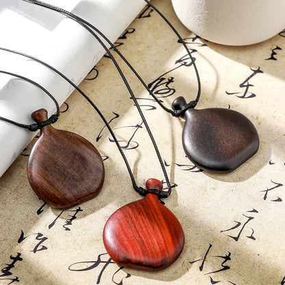 Three wooden pendants on black cords with a textured surface background
