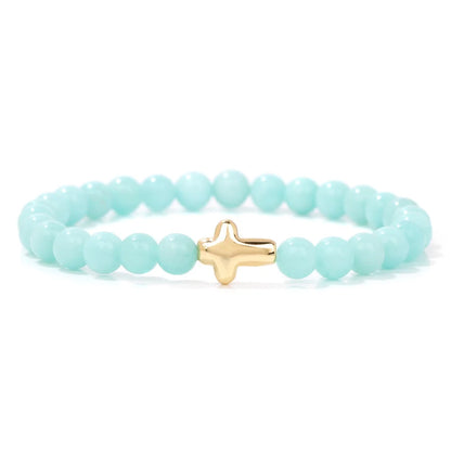Turquoise beaded bracelet with a gold cross charm on a white background