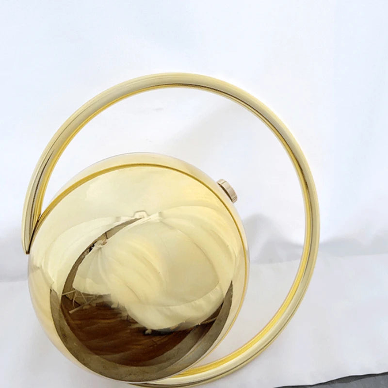 Gold spherical clutch bag with a handle on a white background
