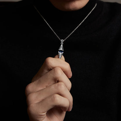 Person holding a silver necklace with a pendant against a dark background