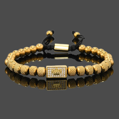Gold beaded bracelet with a rectangular clasp on a reflective surface