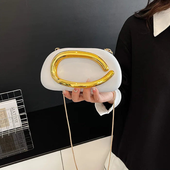 Person holding a white handbag with a gold handle against a black background