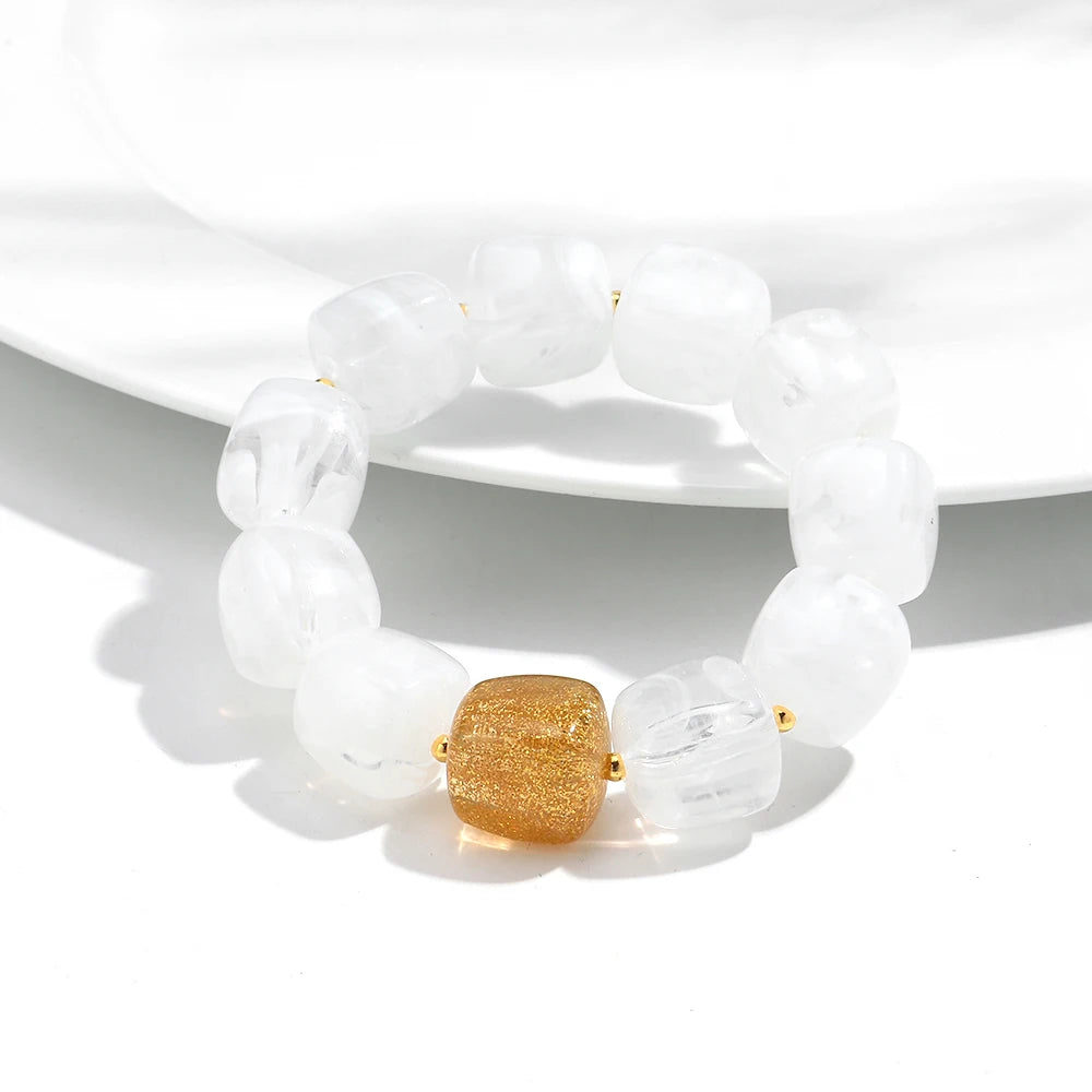 White beaded bracelet with a gold clasp on a white background