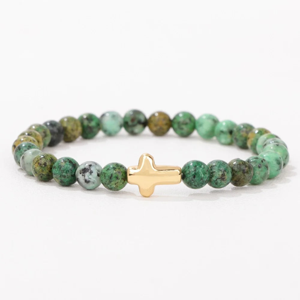 Green beaded bracelet with a gold cross charm on a white background