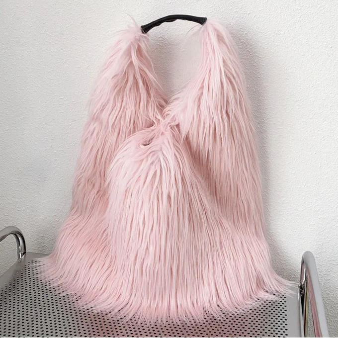Pink fluffy bag on a trolley against a white wall