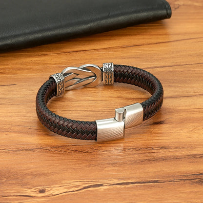 Brown braided leather bracelet with silver clasp on a wooden surface