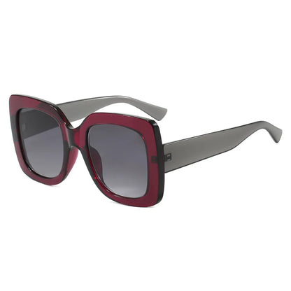 Oversized square sunglasses with a translucent dark red front frame, grey temples, and gradient grey lenses, shown on a plain white background.