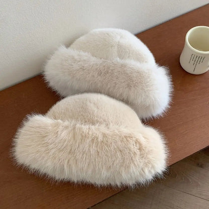 Pair of fluffy hats on a wooden surface with a white wall in the background.
