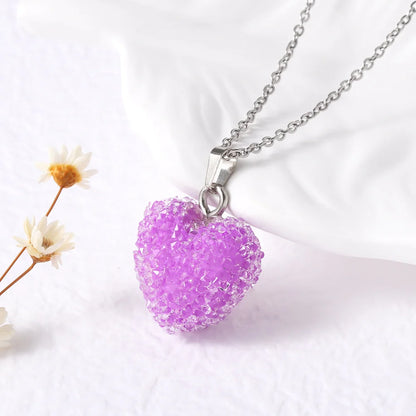 Purple heart-shaped pendant on a silver chain with a white background and small flowers.