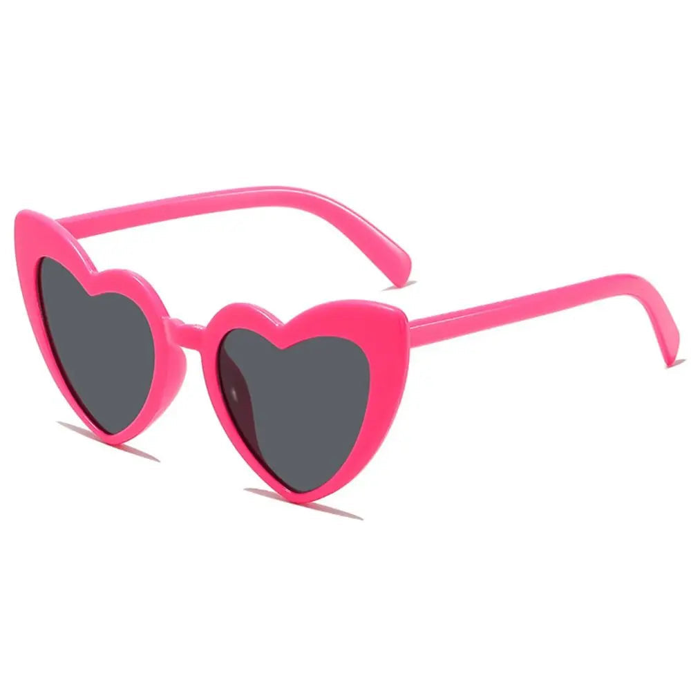 Heart-shaped sunglasses with pink frame and dark lenses on a white background