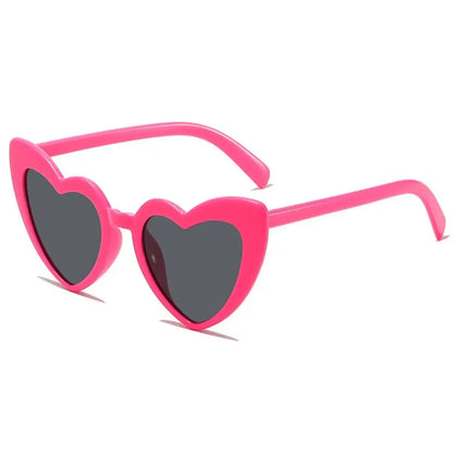 Heart-shaped sunglasses with pink frame and dark lenses on a white background