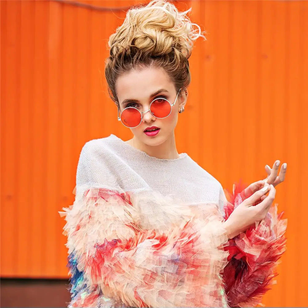 Woman wearing a colorful outfit with a white sweater and floral sleeves against an orange background