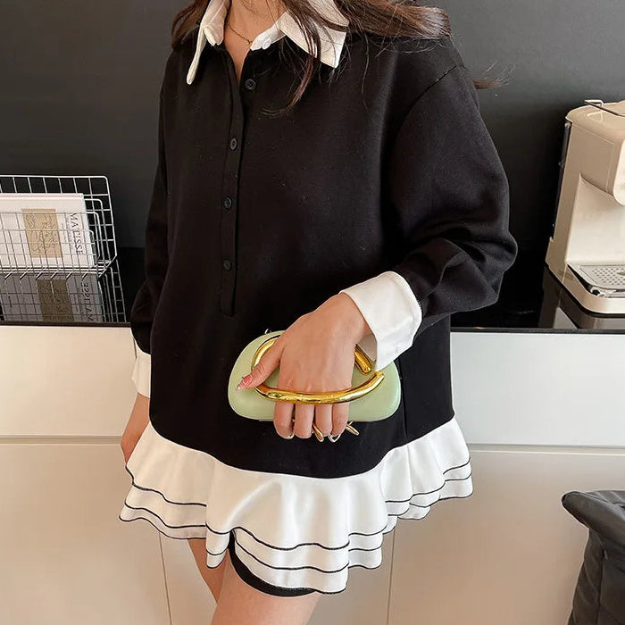 Person wearing a black and white outfit with a green clutch in an indoor setting