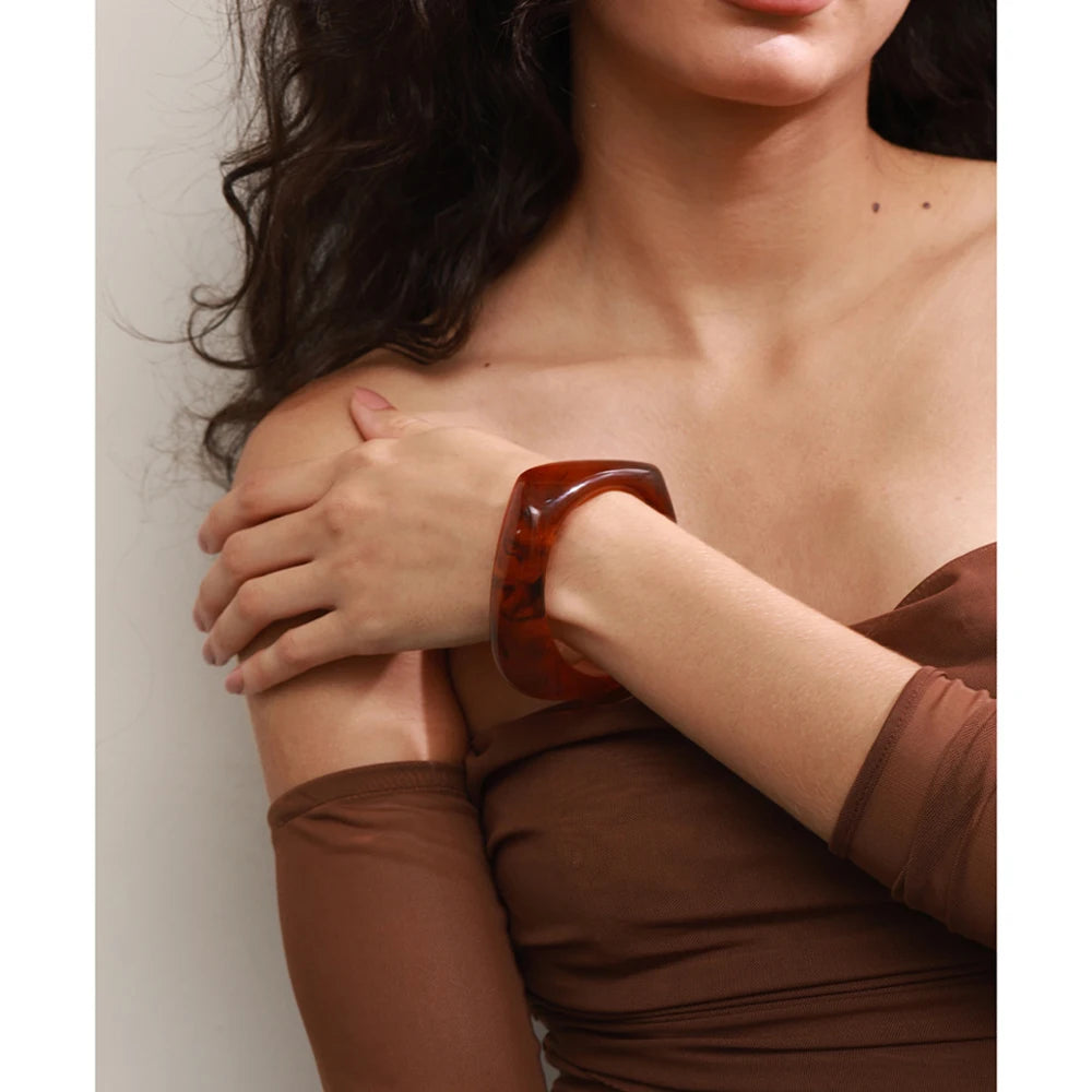 Woman wearing a brown dress with a close-up of her shoulder and arm.