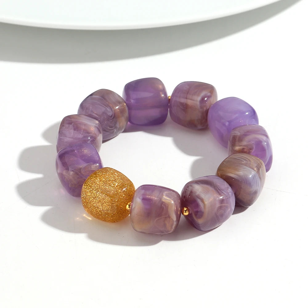 Purple beaded bracelet with a gold bead on a white background