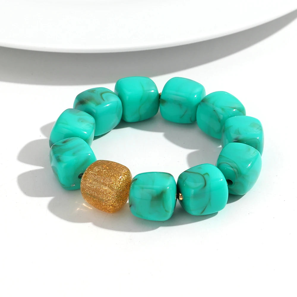 Turquoise beaded bracelet with a gold accent on a white background