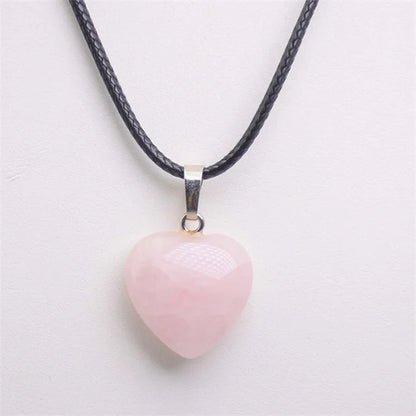 Heart-shaped pink pendant on a black cord against a light grey background