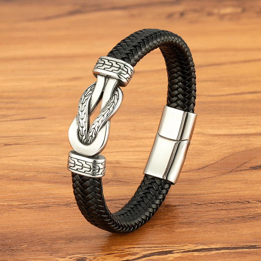 Black braided leather bracelet with silver clasp on a wooden surface