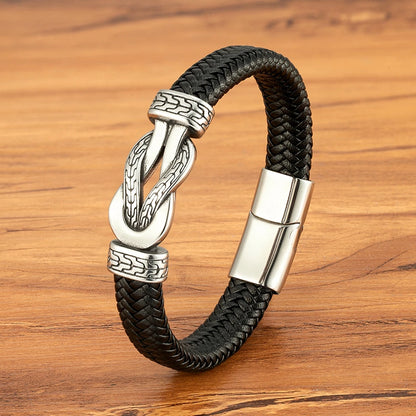 Black braided leather bracelet with silver clasp on a wooden surface