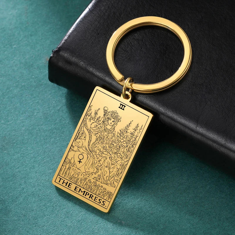 Gold keychain with 'The Empress' tarot card design on a teal surface