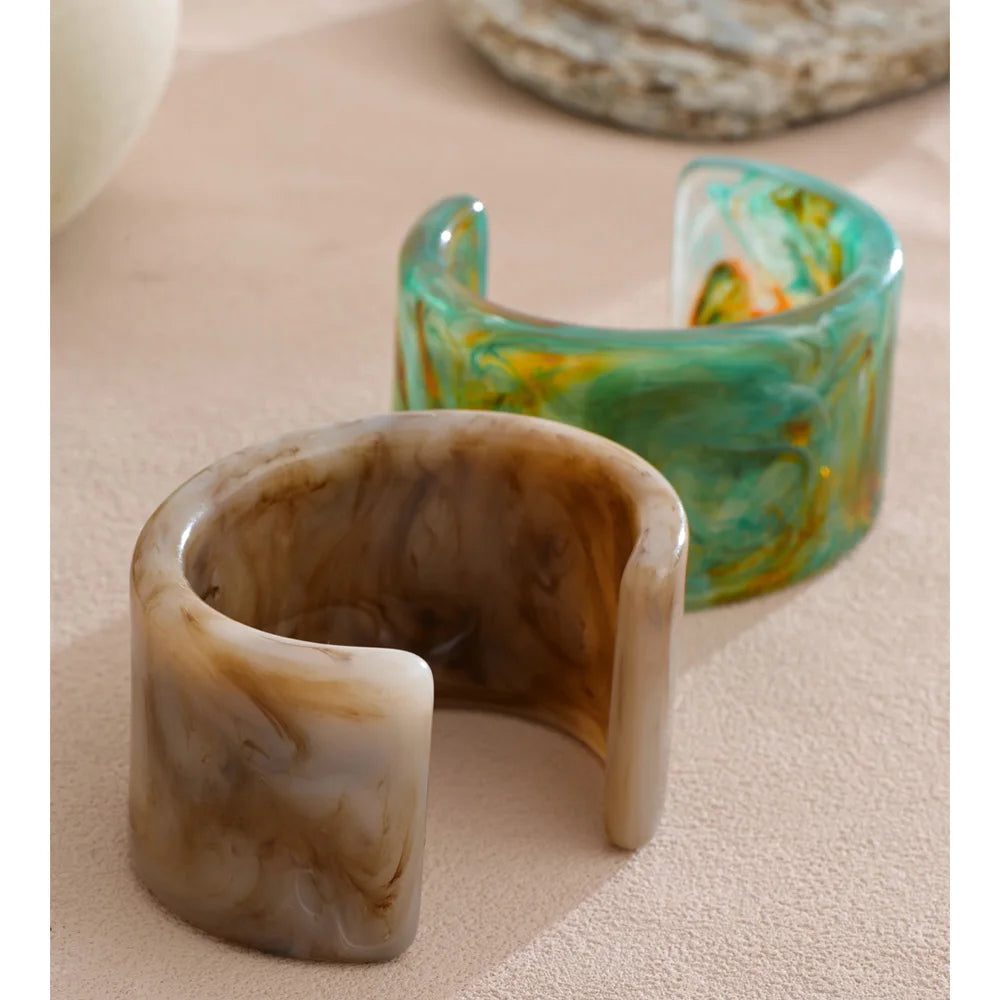 Two marbled cuff bracelets on a beige surface