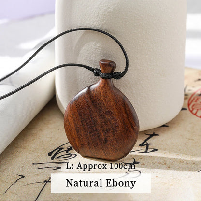 Wooden pendant necklace on a string with a white cylindrical object and textured surface in the background.
