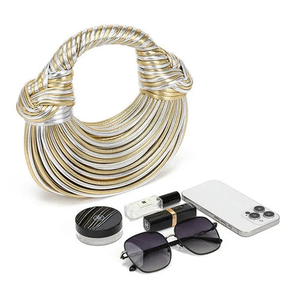 Two-tone gold and silver handbag with a phone, sunglasses, and other items on a white background