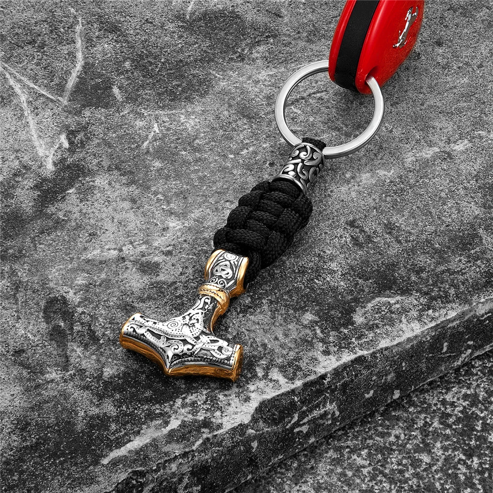 Keychain shaped like a hammer with black cord on a textured surface
