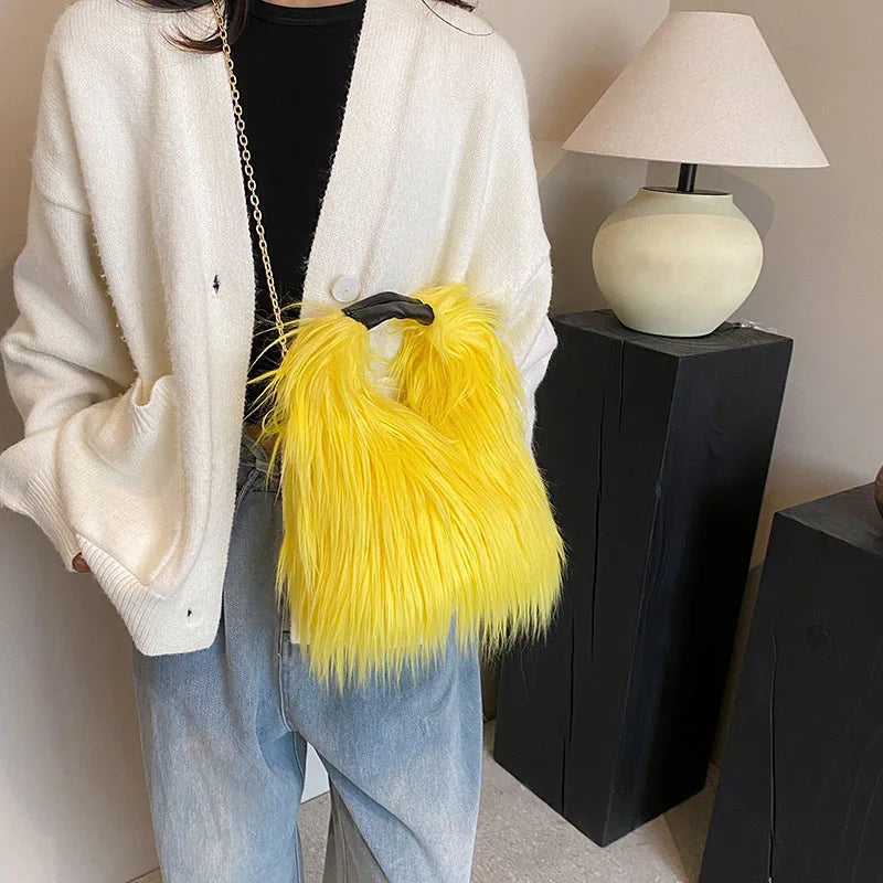 Person holding a yellow furry handbag indoors with a lamp and black stand in the background.