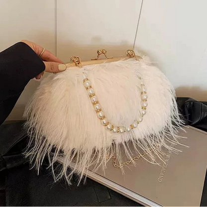White feathered handbag with pearl detailing held by a hand against a neutral background
