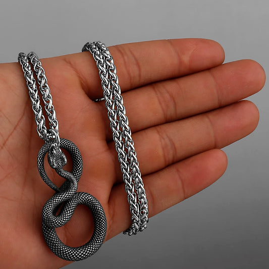 Silver chain necklace with snake design held in a hand against a grey background