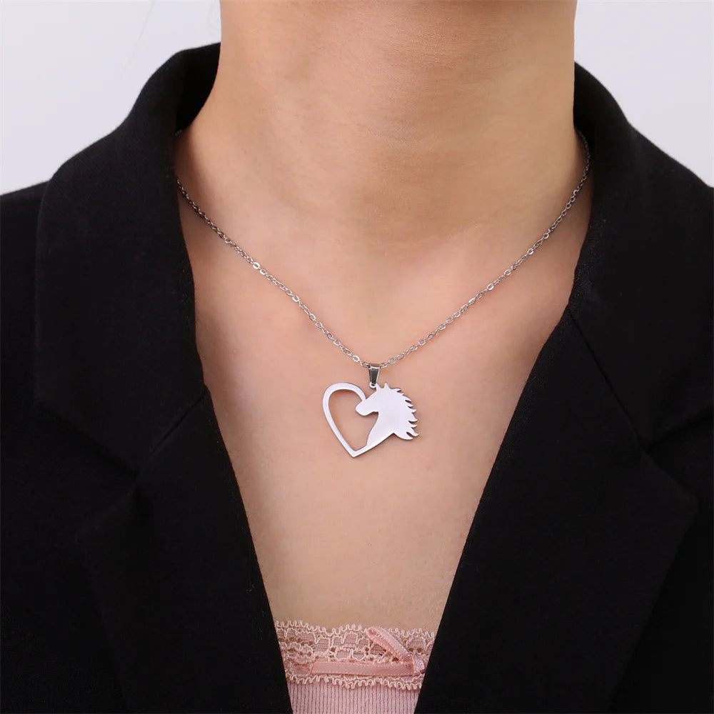 Necklace with a heart-shaped pendant featuring a unicorn design on a person wearing a black blazer.