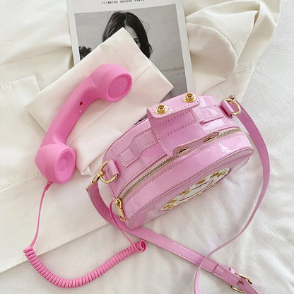 Pink phone-shaped bag with a pink cord on a white surface