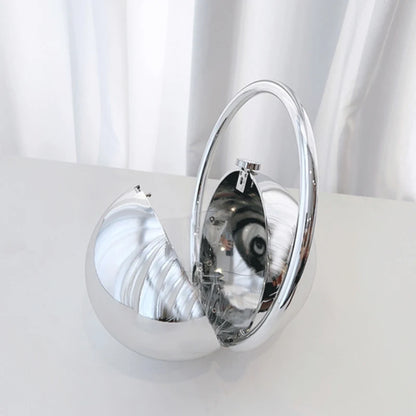 Silver circular clutch bag with reflective surface on a white background